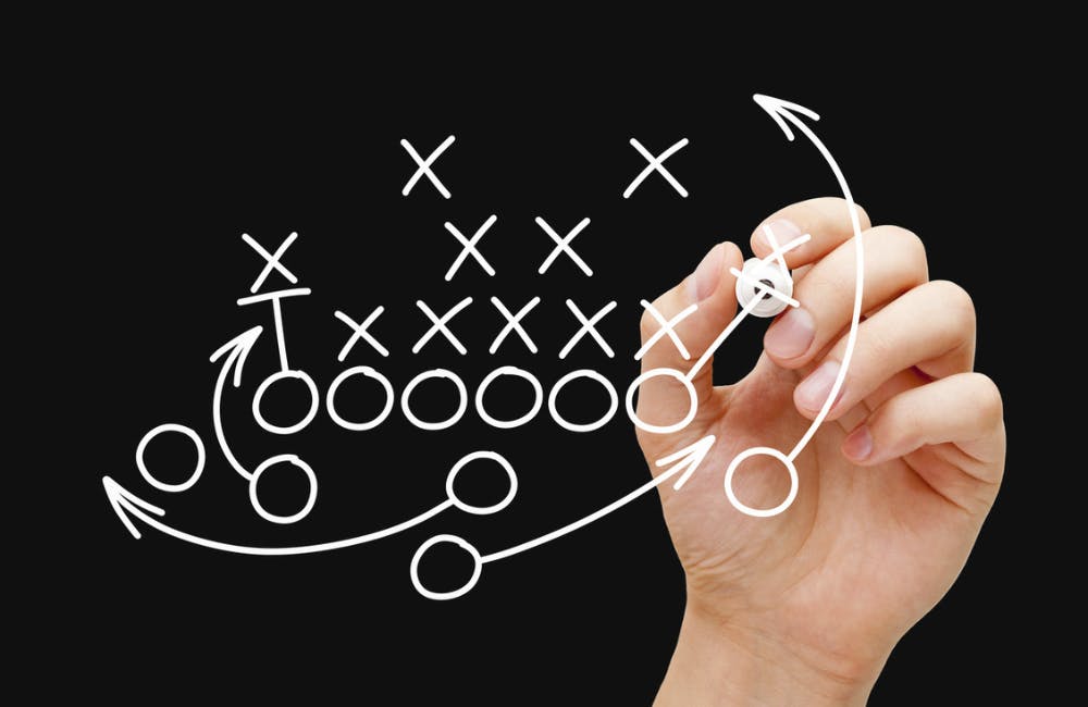Coach drawing american football or rugby game plan, strategy and tactics with white marker on transparent wipe board.
