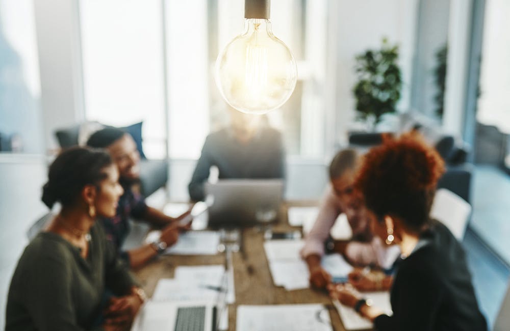 Shot of a group of young businesspeople having a meeting with a lightbulb in the foreground.