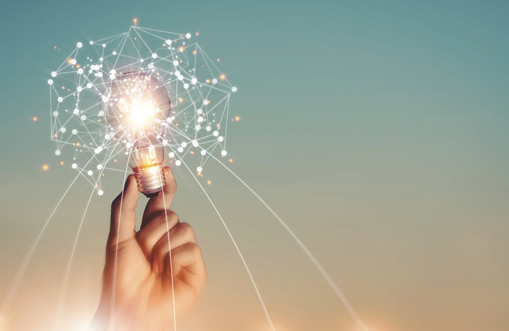 New ideas and imagination Creativity and inspiration Technological innovation. Hand holding brain digital network and abstract science light bulb inside on networking connection on sky background.