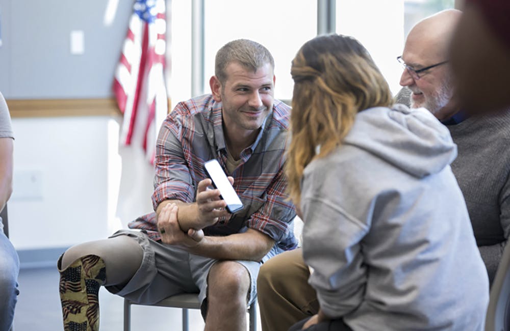 Wounded veteran shows something on smartphone to friends