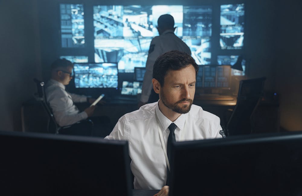 An employee of security, security, police, rescue service, FBI, CIA, sits at his workplace behind monitors. The man works behind two monitors, he studies the received information.