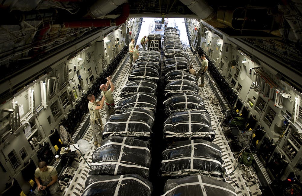 Members of the 8th Expeditionary Air Mobility Squadron and the 421st Quartermaster Company prepare bundles of jet fuel for an airdrop mission on a C-17 Globemaster III.