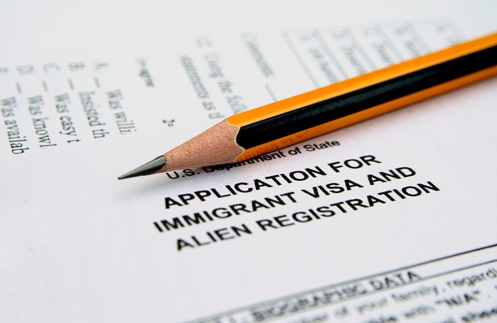 a close-up of a pencil atop an application for immigrant visa and alien registration paper