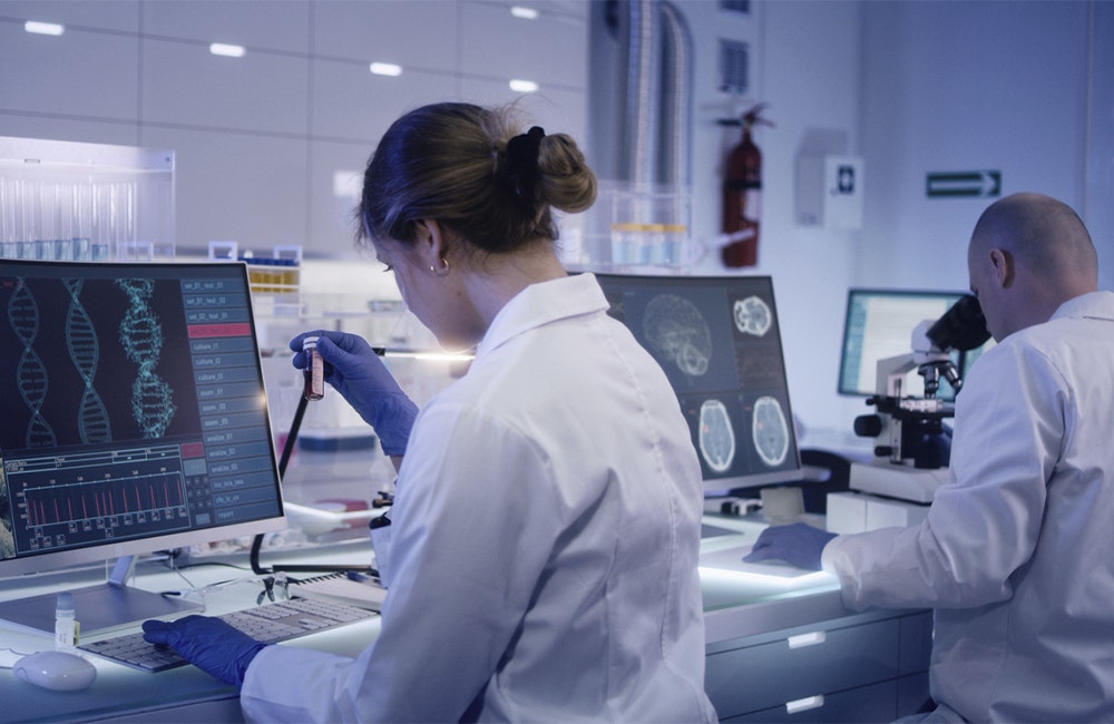 a woman scientist working at a computer screen showing DNA strands