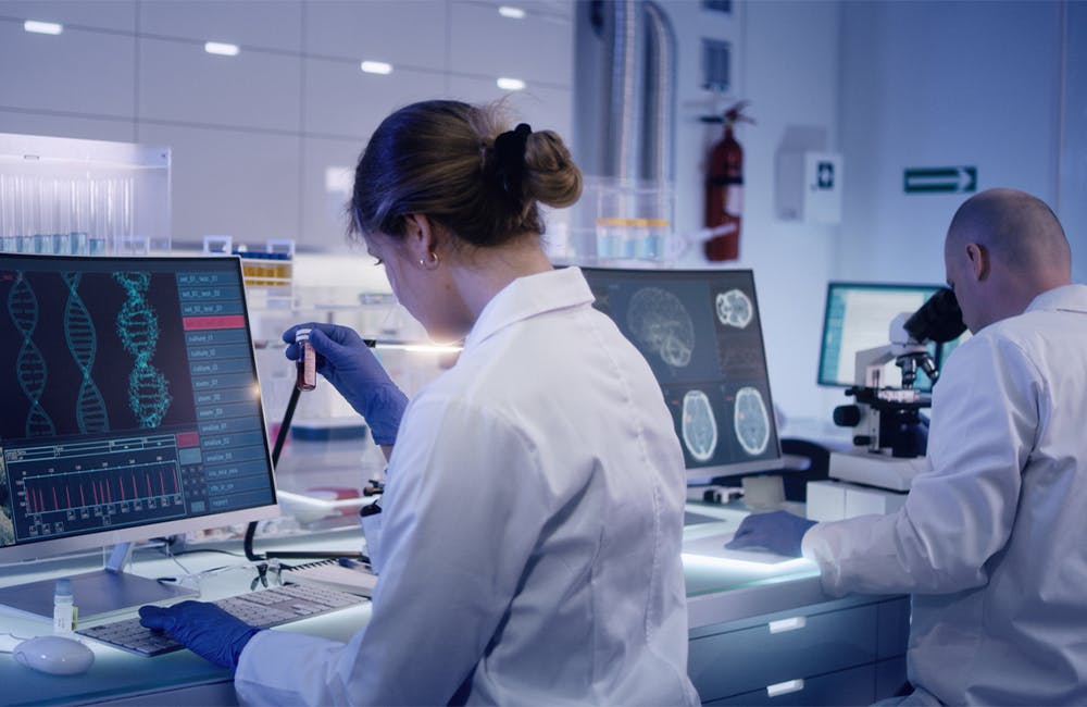 a woman scientist working at a computer screen showing DNA strands