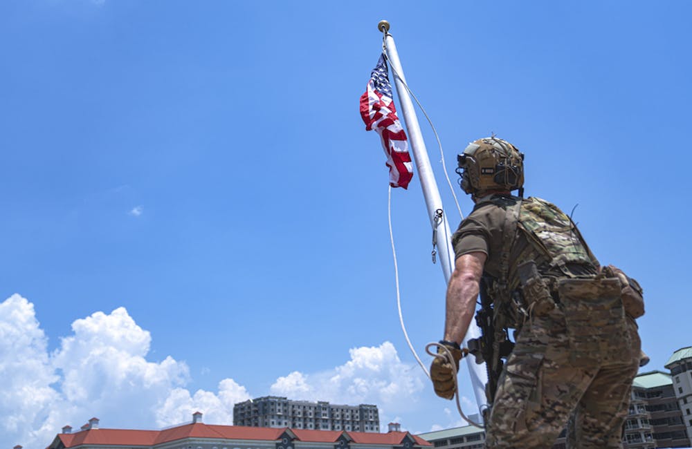 image of a member assigned to U.S. Special Operations Command hoists an American flag on a boat during a Special Operations Forces (SOF) demonstration in Tampa, Florida, May 18, 2022.