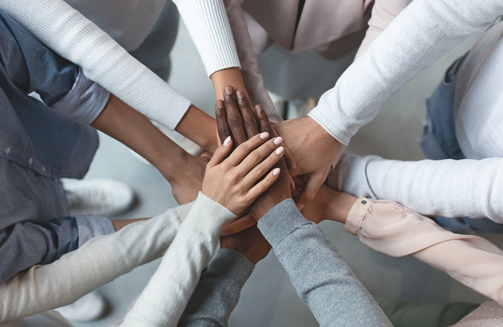 Close up of international business team showing unity with putting their hands together on top of each other.