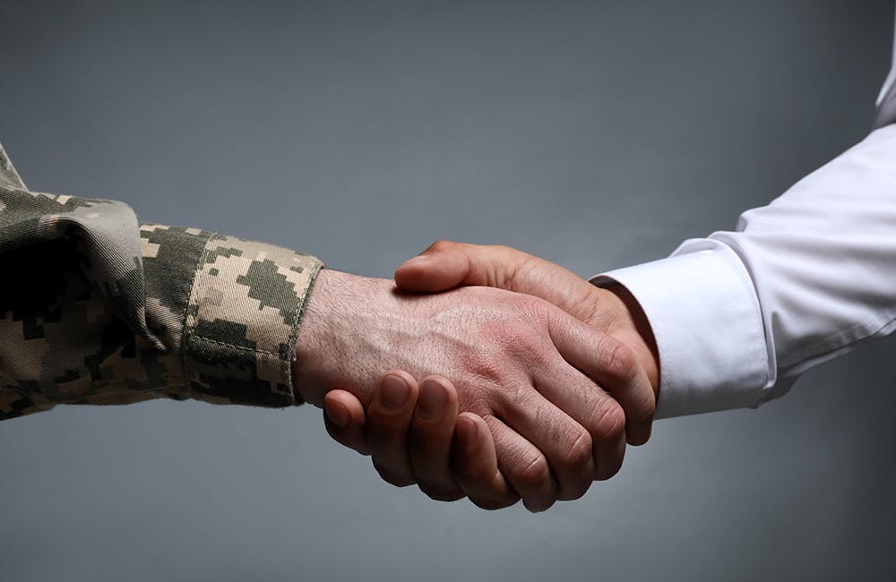 conceptual image of Soldier and businessman shaking hands against grey background representing the army's revealing its new workforce implementation plan for 2022