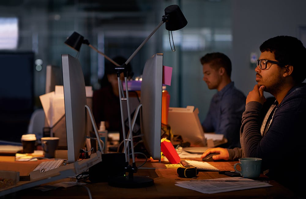 image of group of young coworkers working in a dimly-lit office concept representing a cyber workforce