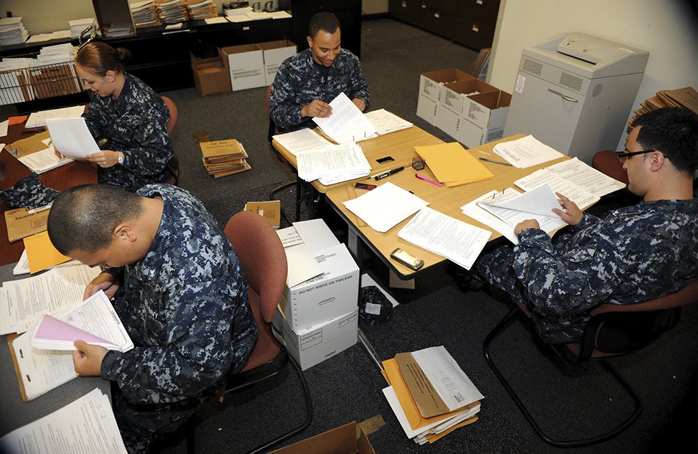 image of four military personnel looking through stacks of paper files which represents CMS and EPA's plans to toll out new tools to help transition from paper to electronic records.
