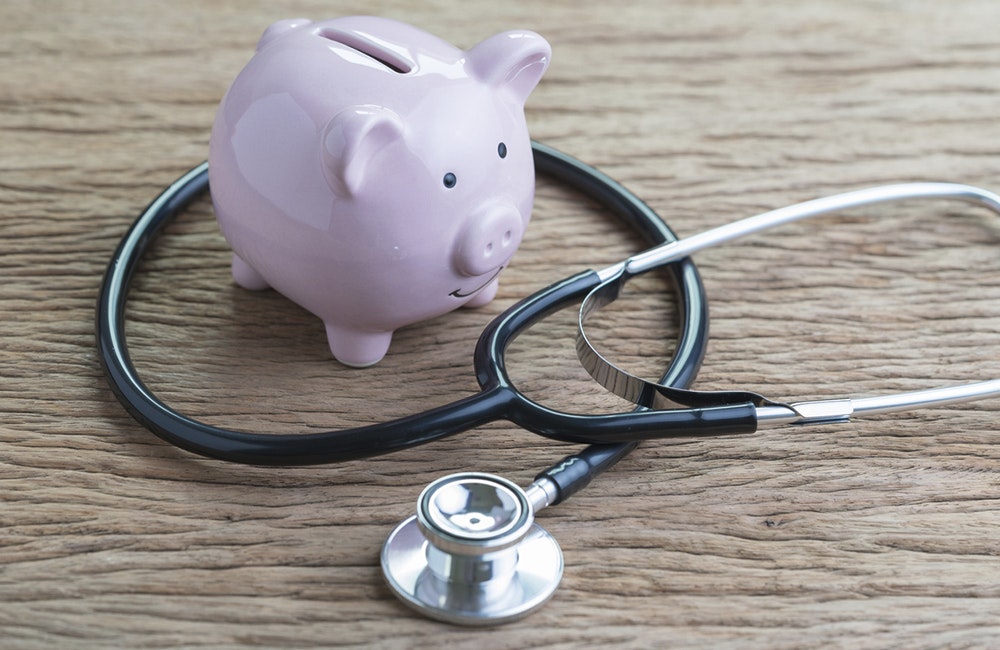 A piggy bank sits next to stethoscope