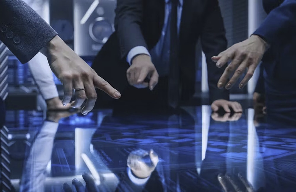 Diverse Team of Government Intelligence Agents Standing Around Digital Touch Screen Table and Satellite Tracking Suspect, Pointing at Display. Big Dark Surveillance Room.