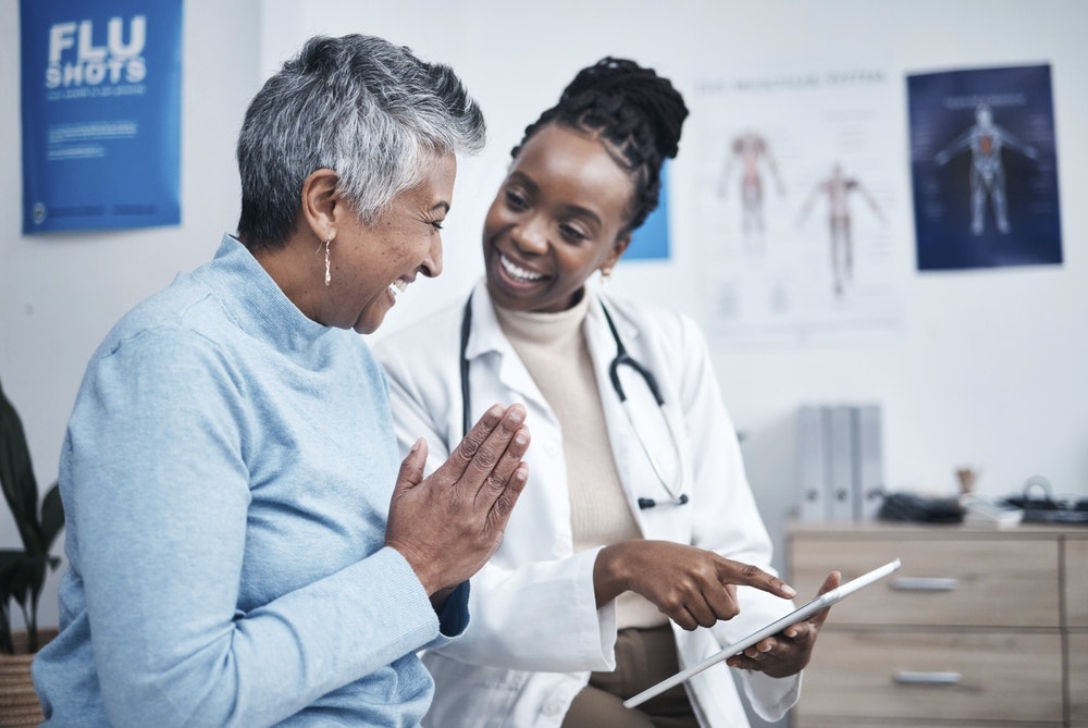 Black woman doctor and elderly patient with good news.