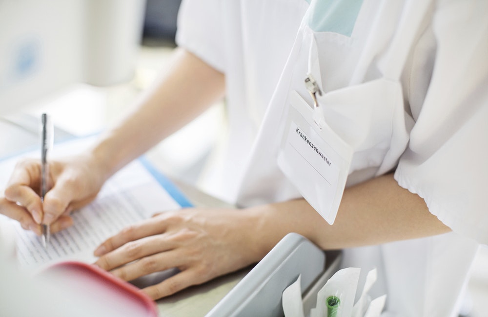 Close up of female nurse writing medical report of patient. Doctor writing medicine prescription.