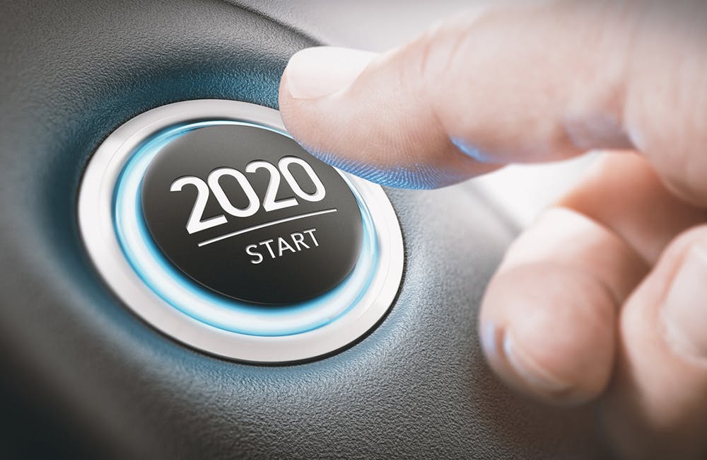 Finger about to press a car ignition button with the text 2020 start. Year two thousand and twenty concept.