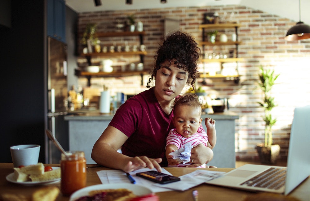 Close up of a mother using a phone with her daughter while having breakfast and doing bills