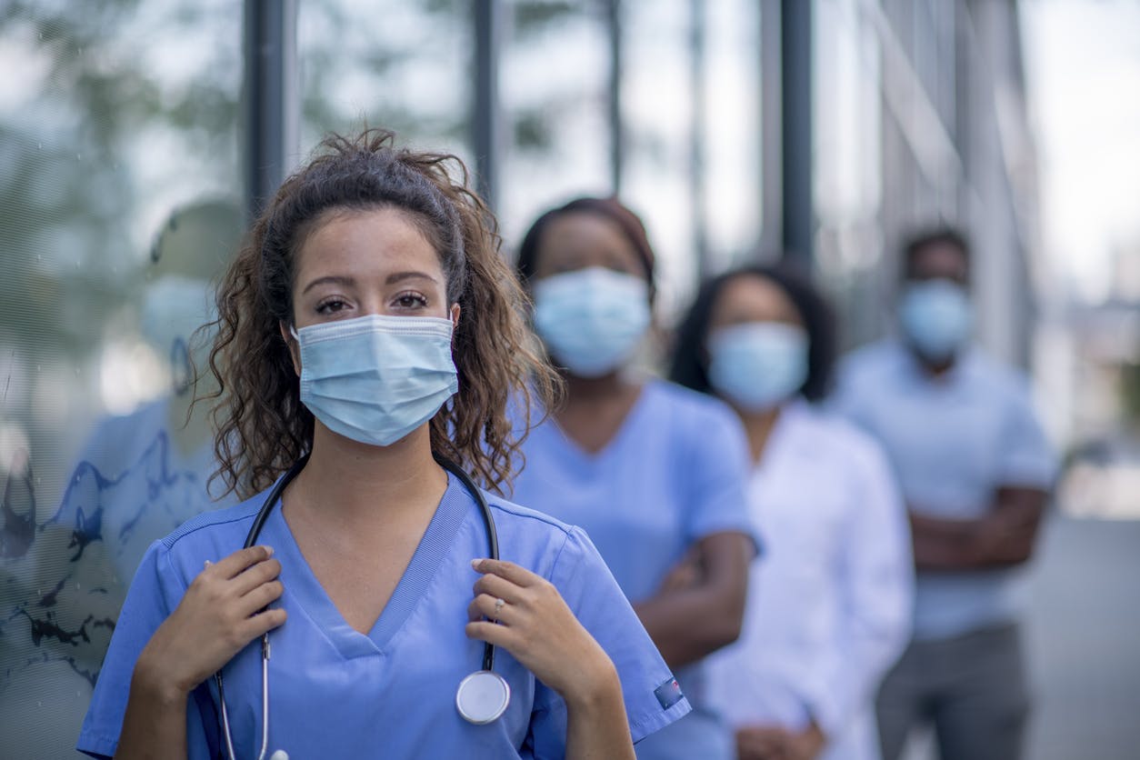 Diverse group of medical professionals outside the hospital wearing protective face masks.