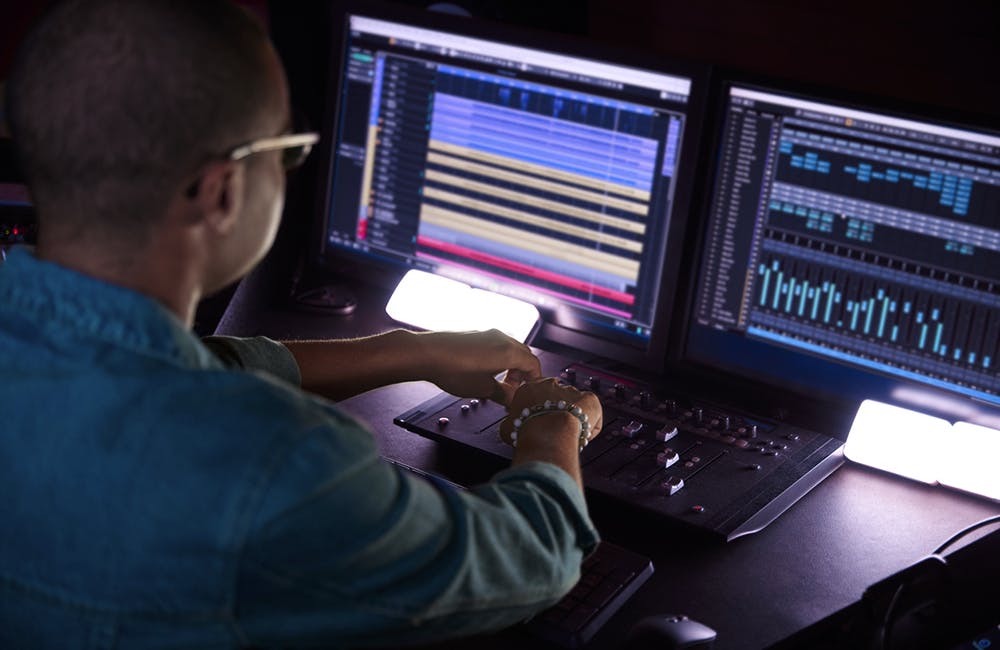 African-american producer working on music track on sound mixer control panel in music studio