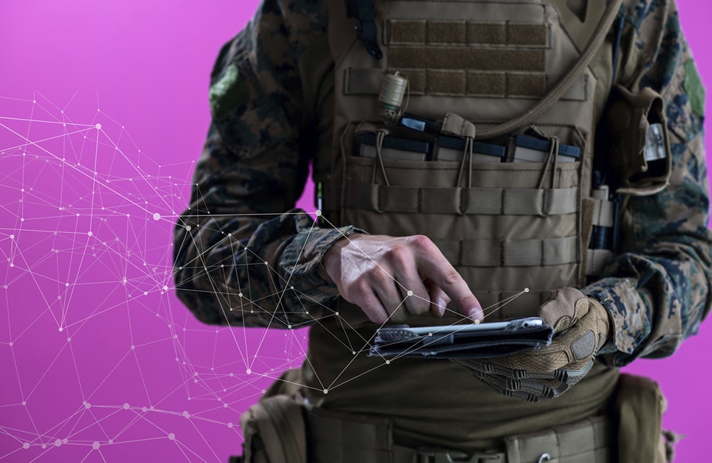 soldier using tablet computer hands closeup pnk background pixelated neural network concept