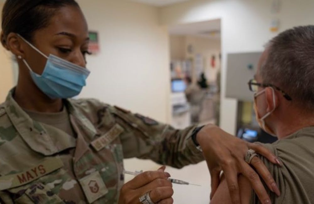 military personnel giving vaccine to a patient