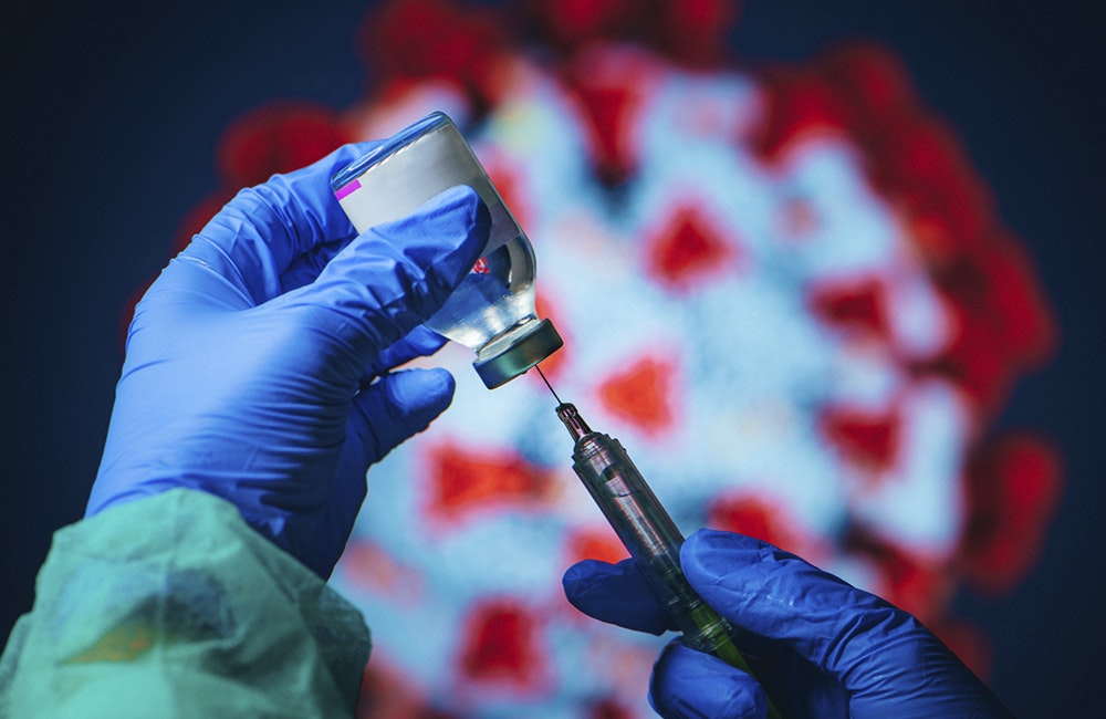 Coronavirus Covid-19 Protection and Vaccine. Doctor drawing up solution from vaccine bottle and filling syringe injection for patient vaccination in medical clinic, Coronavirus in background