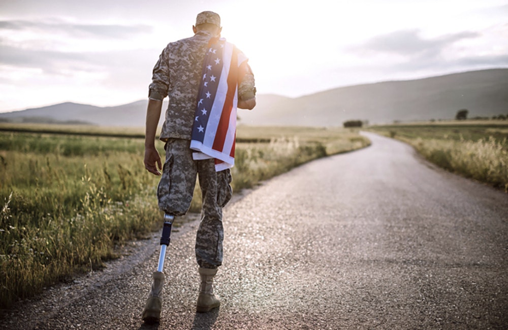 Rear View Of Young Amputee Soldier Walking Road Wearing American Flag