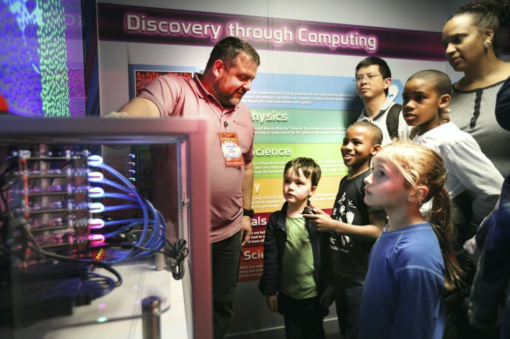 Researchers and kids look at a super computer
