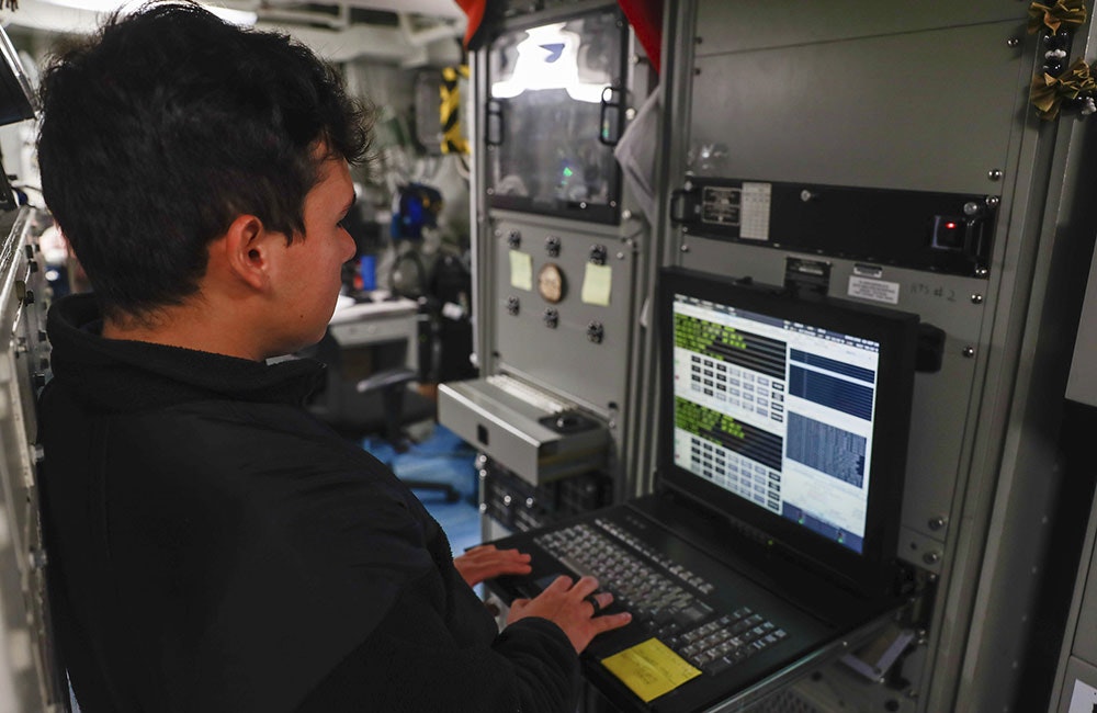 A Navy electronics technician works on a computer aboard the Arleigh Burke-class guided-missile destroyer USS Michael Murphy in 2024.
