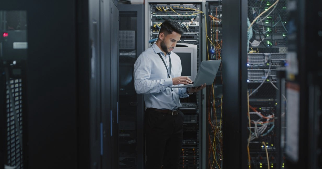 Man looking at a laptop in a server room