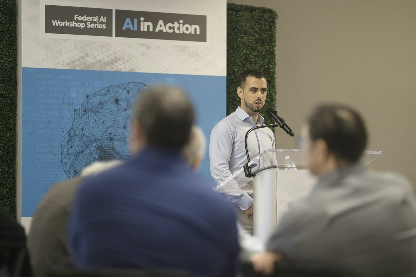 A speaker addresses a crowd of federal IT professionals during GovCIO Media & Research's AI in Action workshop.