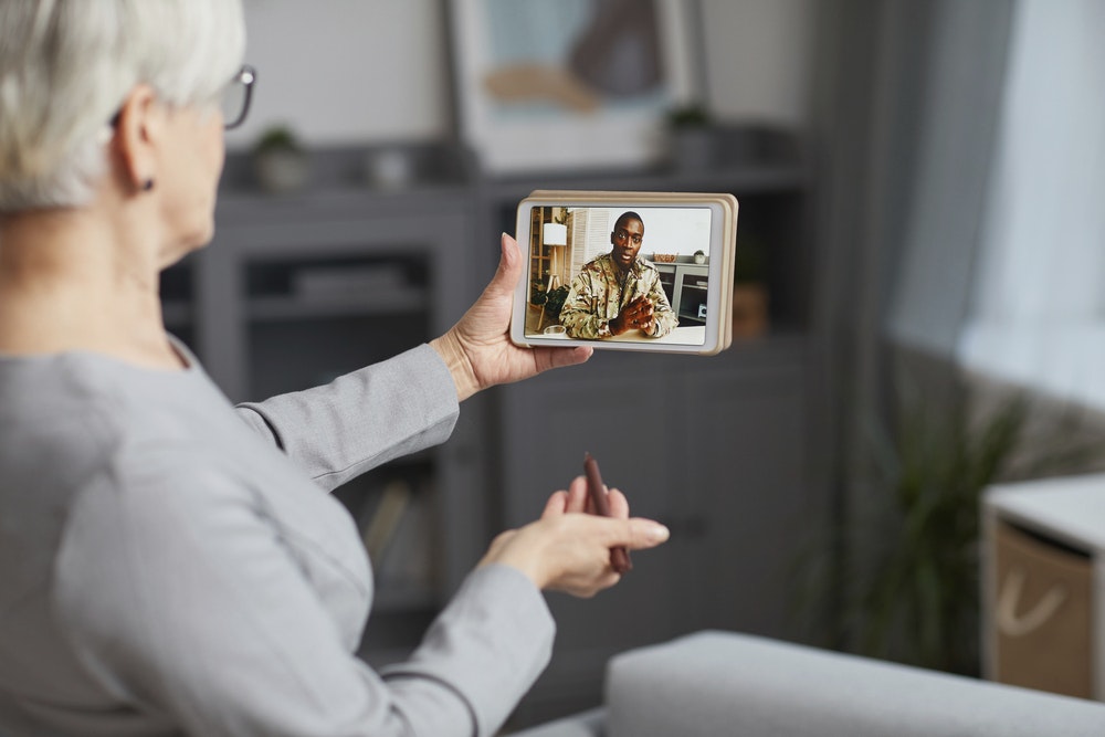 A woman uses a screen to communicate with a veteran.