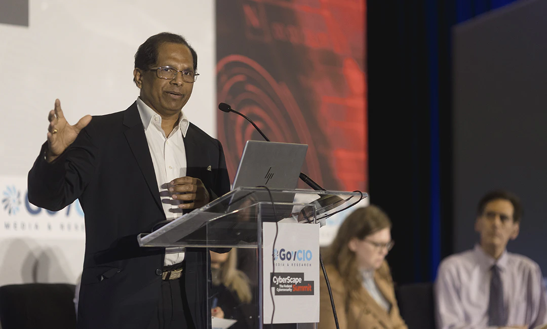 Photo taken during GovCIO Media & Research's CyberScape: The Federal Cybersecurity Summit's Lightning Rounds: Snapshots in Cybersecurity. The image features Sai Sravan Cherukuri speaking at a podium with Cheri Pascoe, Director, National Cybersecurity Center of Excellence (NCCoE), NIST and Rudolf Rojas, IT Program Manager and Security Lead, USDA sitting down in the background.