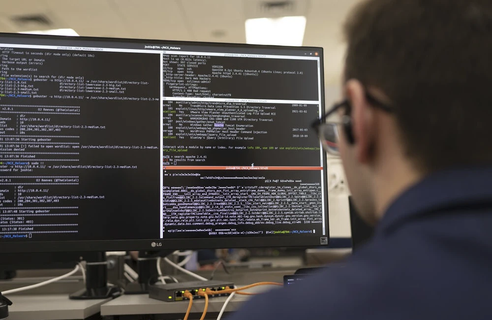 Lines of code on a computer screen in front of a U.S. Coast Guard academy cadet.