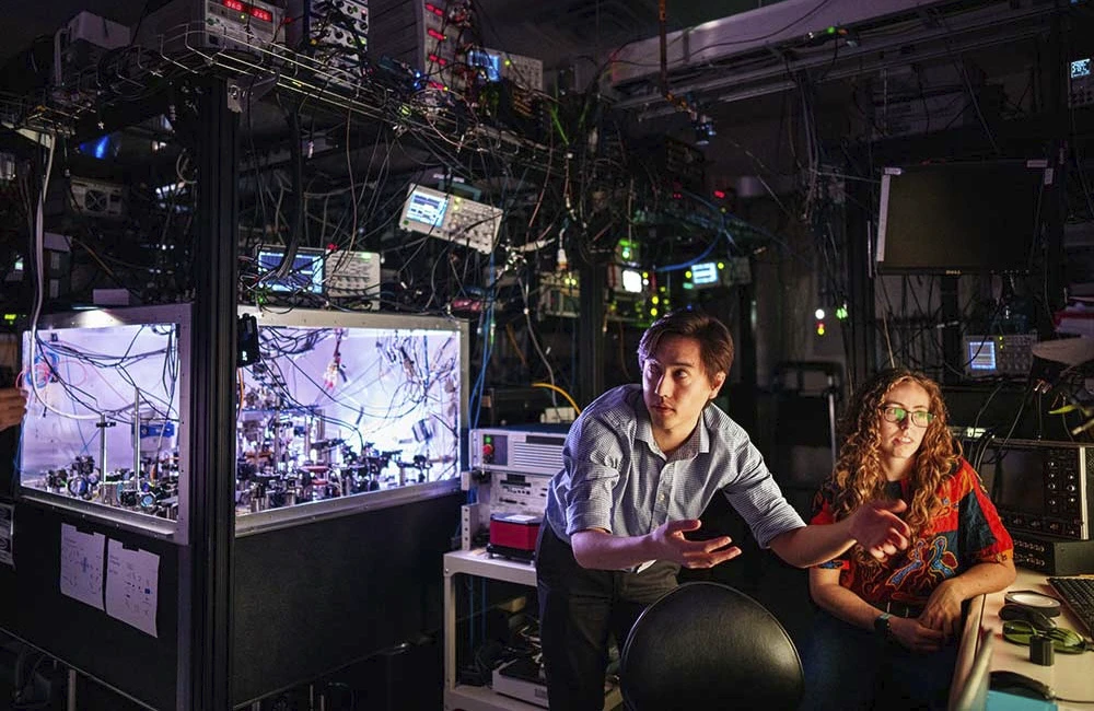 Matthew Chow, center, and Bethany Little discuss with Yuan-Yu Jau, off camera, the first practical way to detect atom loss for neutral-atom quantum computing at Sandia.